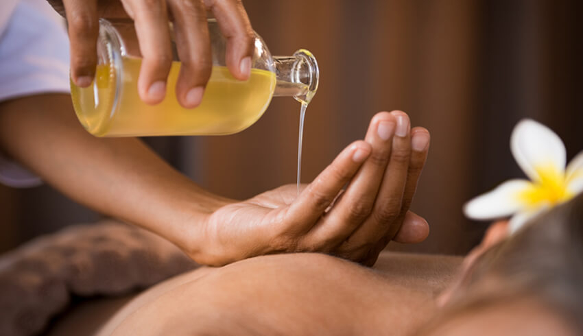 Oil for body massage being poured into a cupped hand